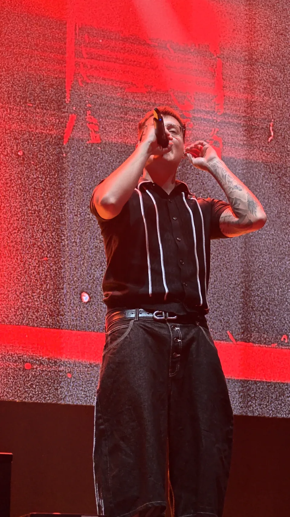 Cantante de música urbana actuando ante una pantalla roja en Reve Fest