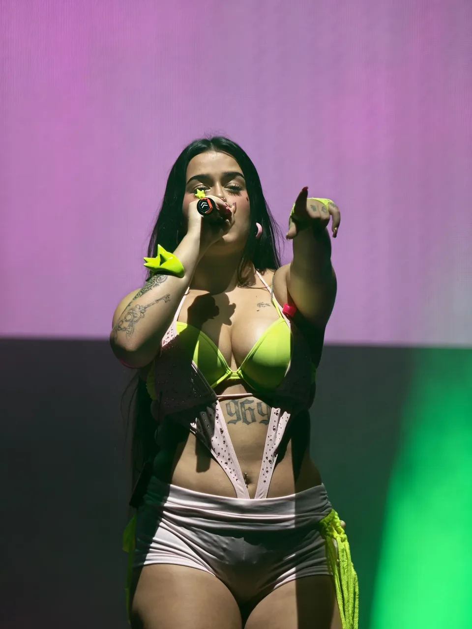 Artista cantando en Reve Fest con visuales verdes al fondo